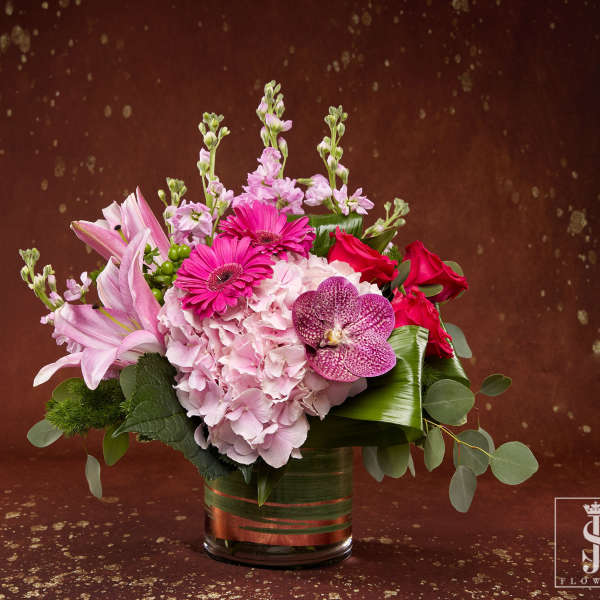 Pink and red mixed flower arrangement in a glass vase