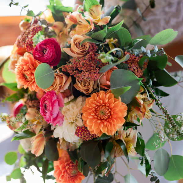 Bride holding a colorful bouquet with orange and pink flowers