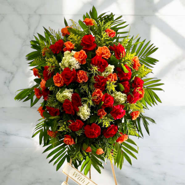 Large standing spray of red and orange roses with white blooms