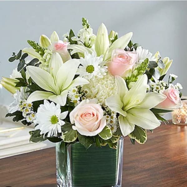 White lilies and pale pink roses in a glass vase
