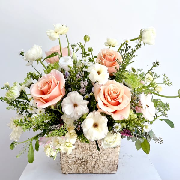 Peach and white rose arrangement in a textured square container