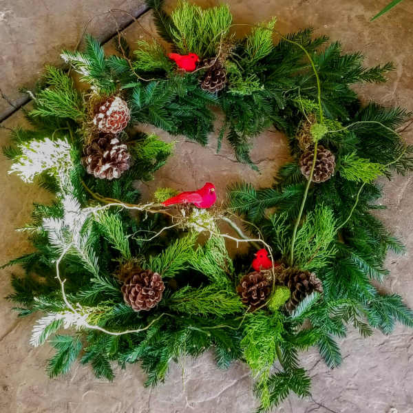 Circular evergreen wreath with pinecones and small red bird ornaments