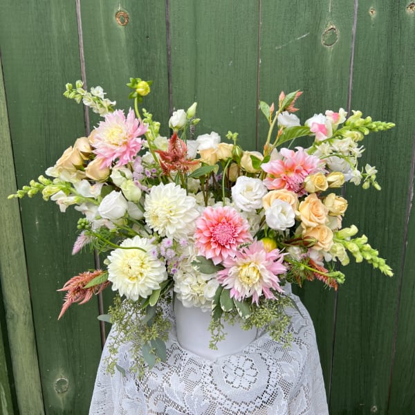Mixed bouquet of pink, white, and peach flowers in a white vase