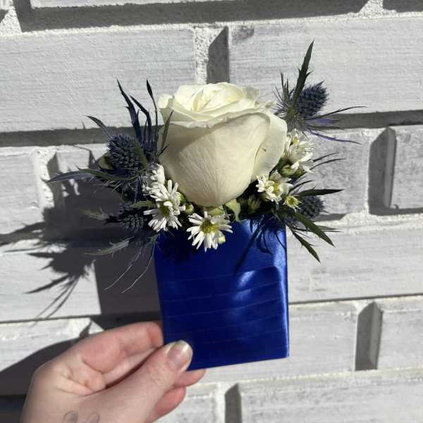 White rose boutonniere with blue ribbon wrap and small white daisies