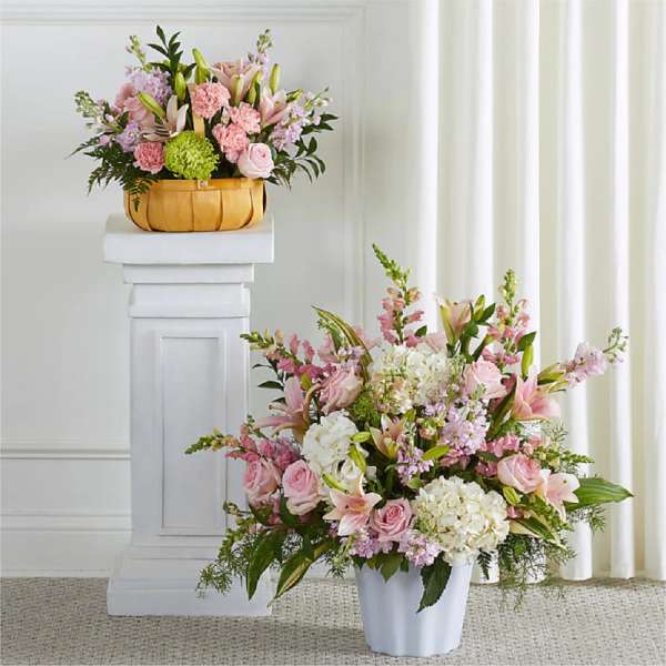 Pink and white floral arrangements in a basket and white vase