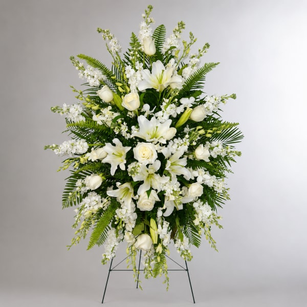 White lilies and roses in a standing floral spray with greenery