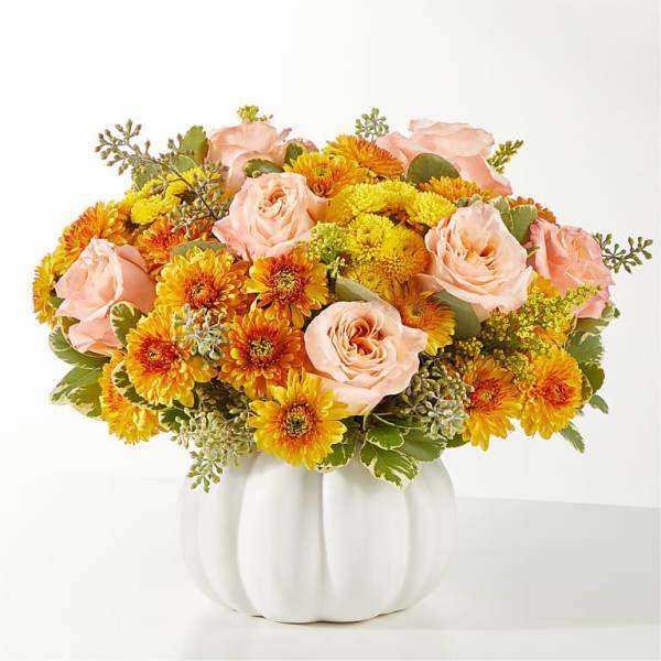 Peach roses and yellow-orange mums in a white pumpkin vase