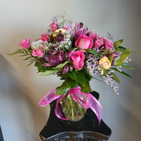 Pink and purple mixed bouquet in a glass vase with a pink ribbon