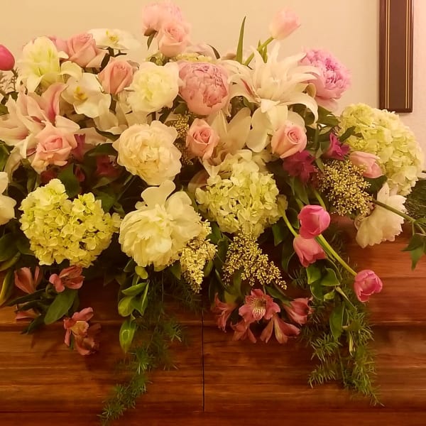 Casket spray with pink and white flowers and trailing greenery