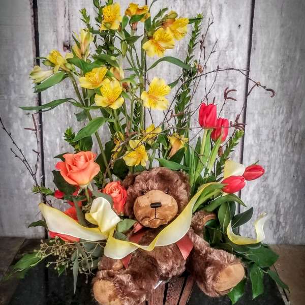Flower arrangement with a teddy bear, roses, tulips, and yellow blooms