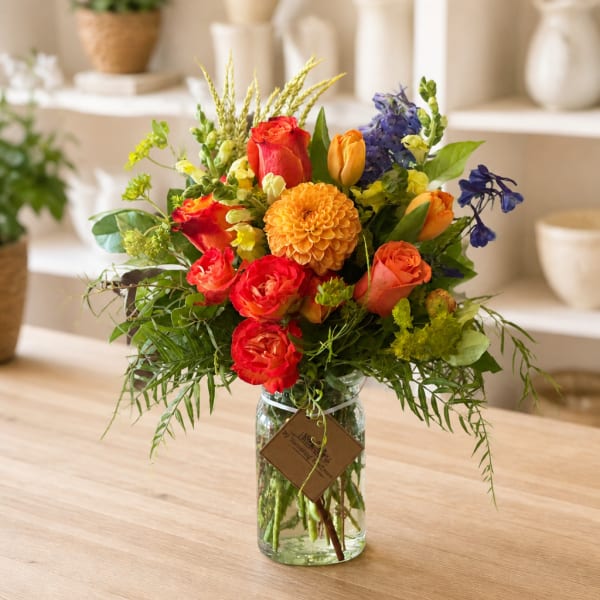 Mixed bouquet of roses, tulips, and a dahlia in a glass jar vase