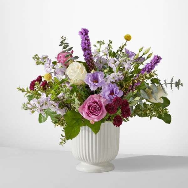 Mixed bouquet of pink, white, and purple flowers in a white vase