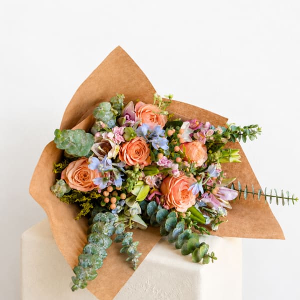 Peach roses and pastel flowers wrapped in brown paper