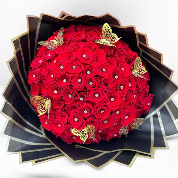 Round bouquet of red roses with gold butterfly accents in black wrap