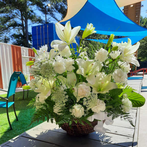 White lilies and carnations arranged in a wicker basket