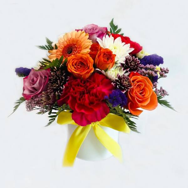 Mixed bouquet of roses, gerbera daisies, and chrysanthemums in a white vase with yellow ribbon