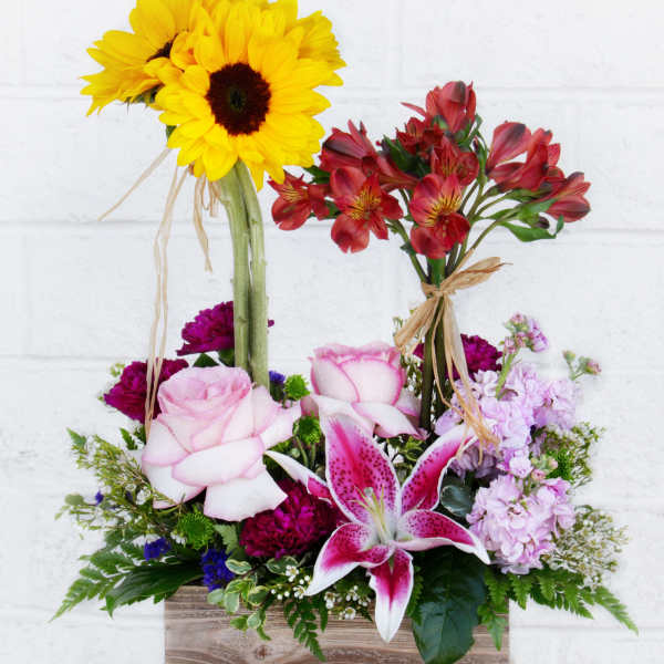 Mixed bouquet with sunflowers, roses, lilies, and red alstroemeria in a wooden box