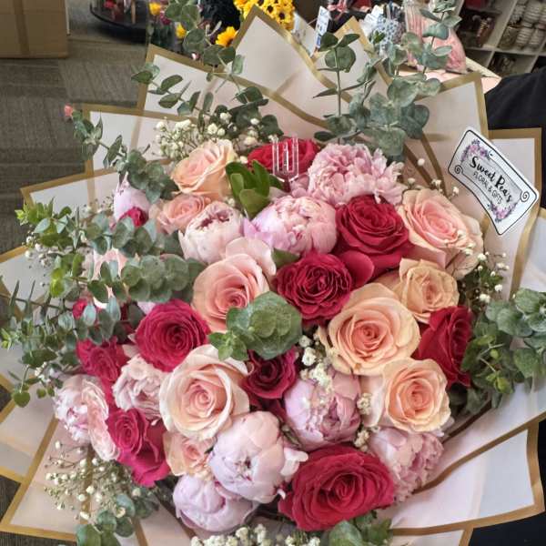 Hand-tied bouquet of pink and red roses with eucalyptus