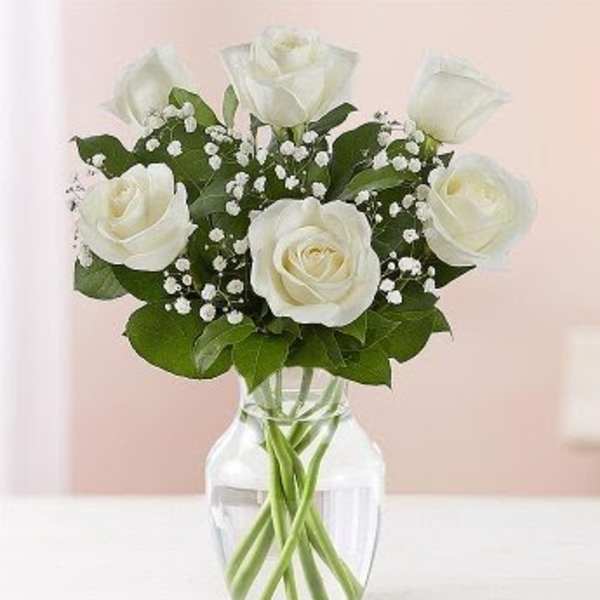 White roses in a clear glass vase with baby's breath