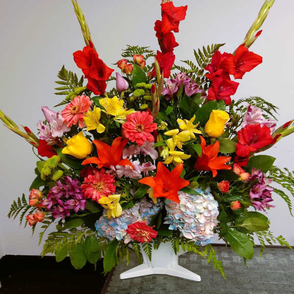 Colorful mixed flower arrangement in a white pedestal vase