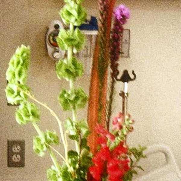 Tall arrangement with red and purple flowers in a black vase