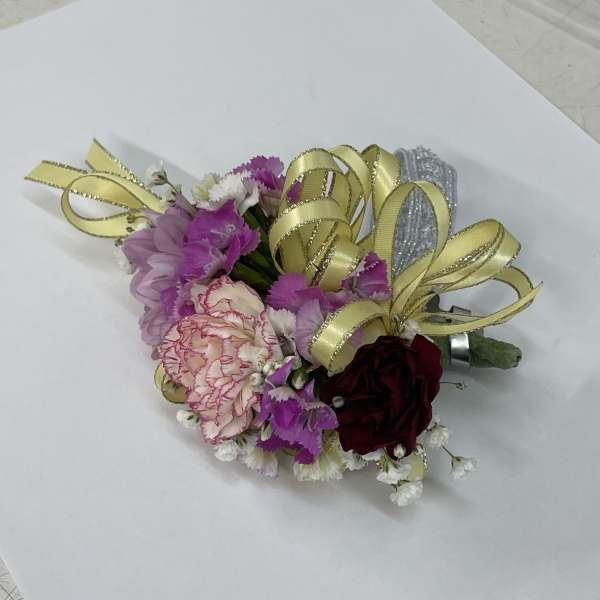 Small corsage with pink and burgundy flowers and gold ribbon loops