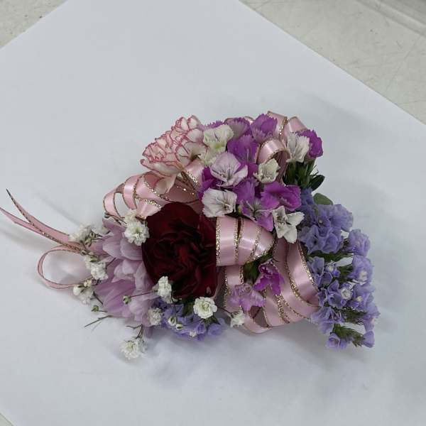 Small bouquet of pink, purple, and white flowers with ribbon accents