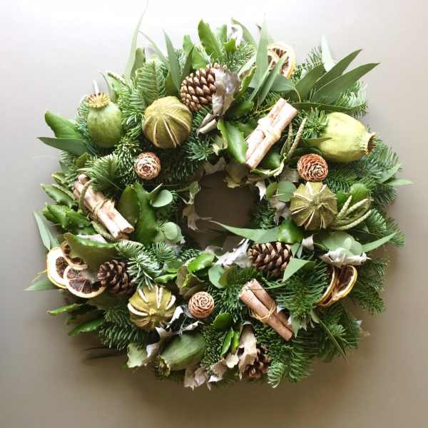 Green holiday wreath with pinecones, dried citrus, and cinnamon sticks