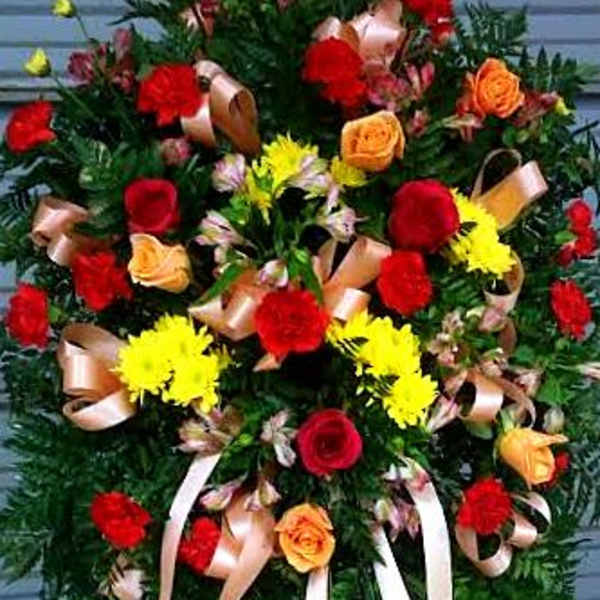 Standing floral spray with red and yellow roses and ribbon streamers