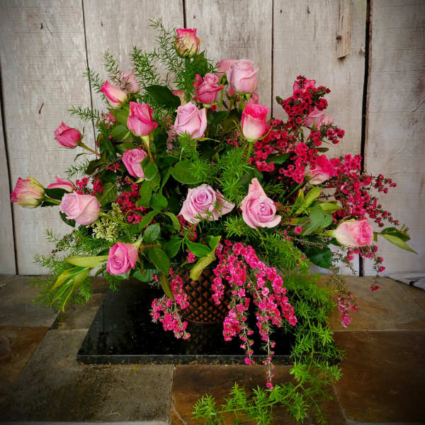 Pink roses arranged in a basket with trailing pink filler flowers