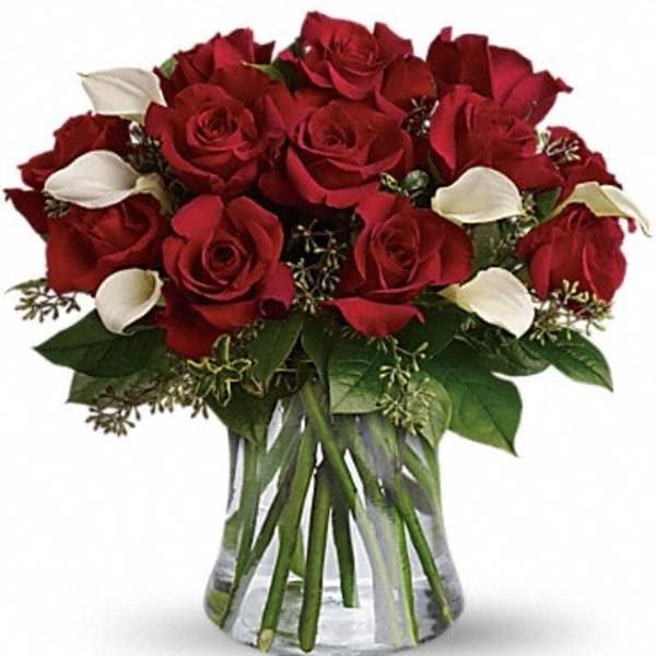 Bouquet of red roses and white calla lilies in a clear glass vase