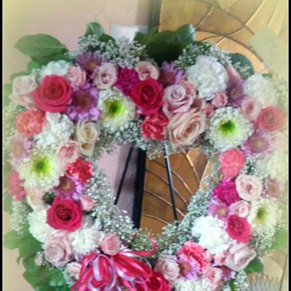 Heart-shaped floral wreath with pink and white roses on an easel