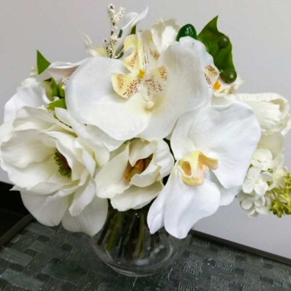 White orchids and tulips arranged in a clear glass vase