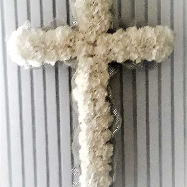 White floral cross on a ribbed gray background