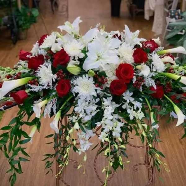 Large floral spray with red roses, white lilies, and cascading greenery