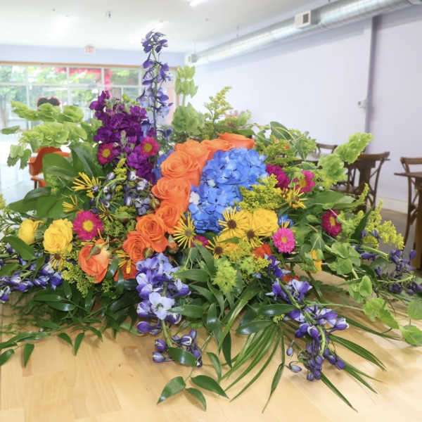 Large colorful floral arrangement with roses, hydrangeas, and purple blooms on a table