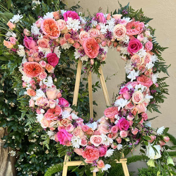 Heart-shaped floral wreath on an easel with pink and white flowers