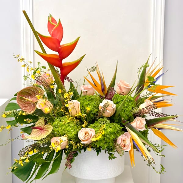 Tropical floral arrangement with pink roses and bird of paradise in a white vase