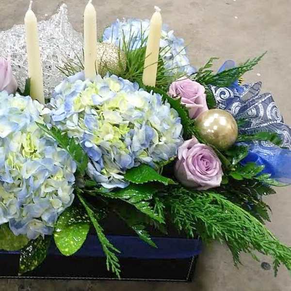 Blue hydrangeas and lavender roses arranged with candles and ornaments in a box