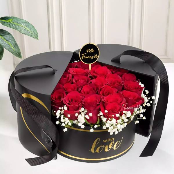 Red roses in a black round gift box with white filler flowers