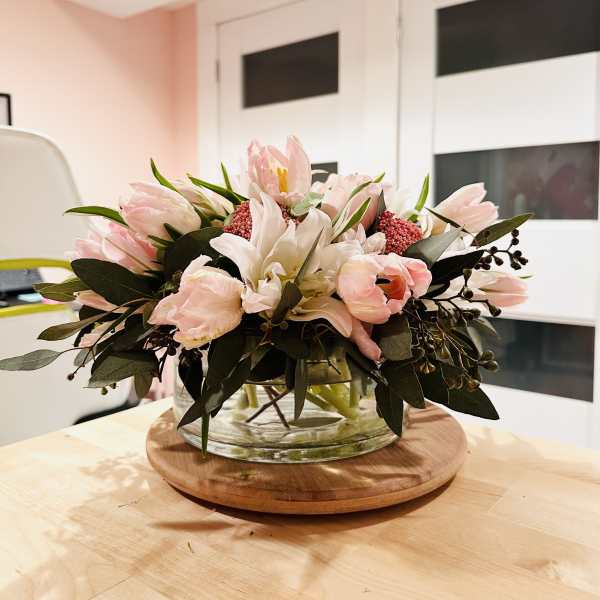 Low floral arrangement of pale pink and white blooms in a glass bowl