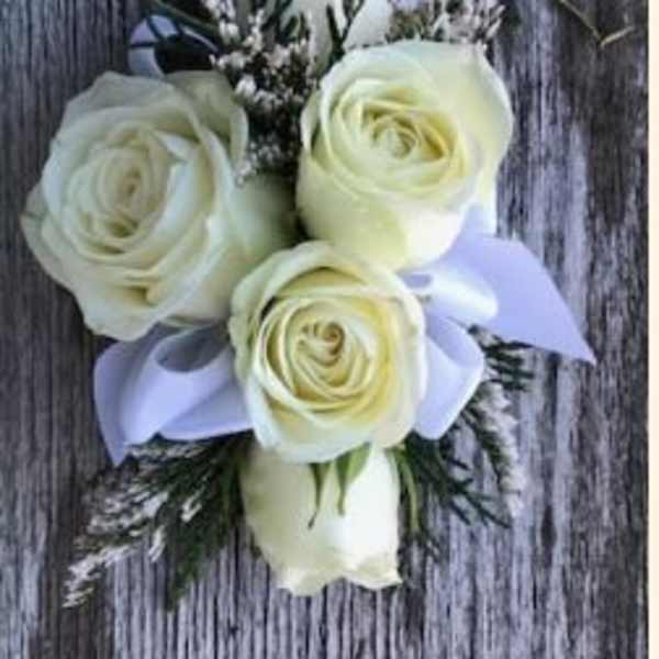 White rose boutonniere with a lavender ribbon on a wood background