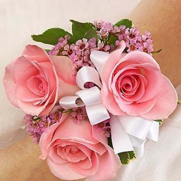 Pink rose wrist corsage with white ribbon and small purple filler flowers