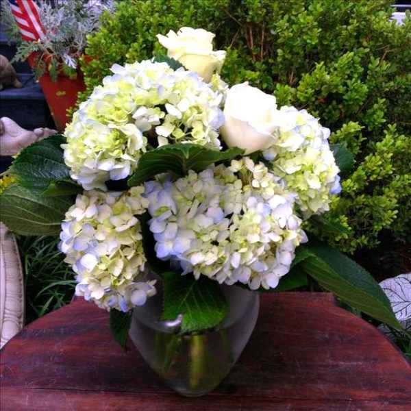 White hydrangeas and roses arranged in a metallic vase