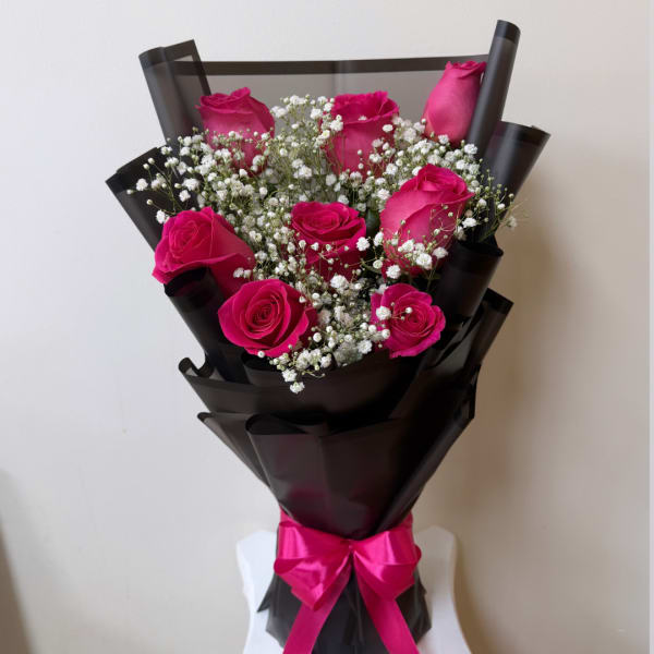 Bouquet of hot pink roses with baby's breath in black wrap and a pink ribbon