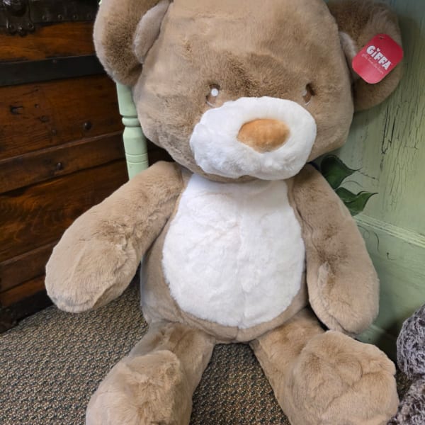 Large brown and white plush teddy bear sitting on the floor