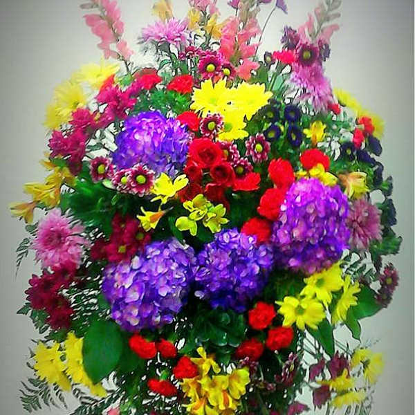 Large standing spray of mixed bright flowers on an easel