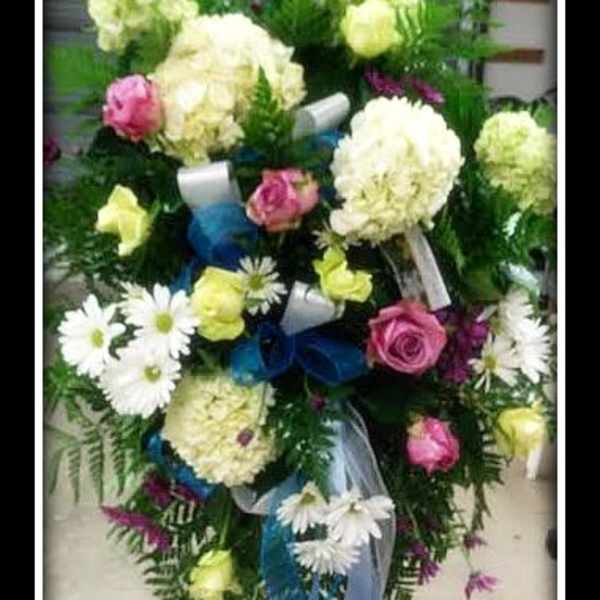 Standing floral spray with white blooms, pink roses, and blue ribbon