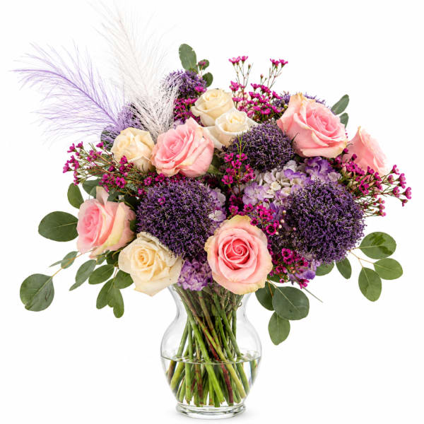 Pink and cream roses in a clear glass vase with purple accents