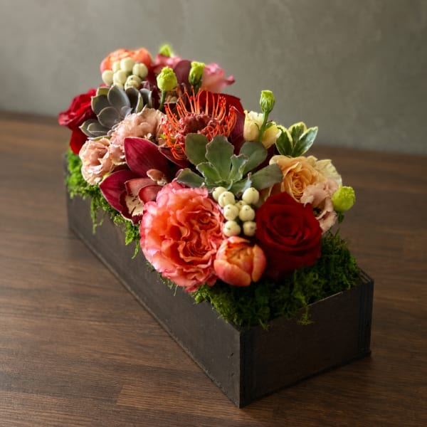 Mixed floral arrangement in a black rectangular box with succulents and roses